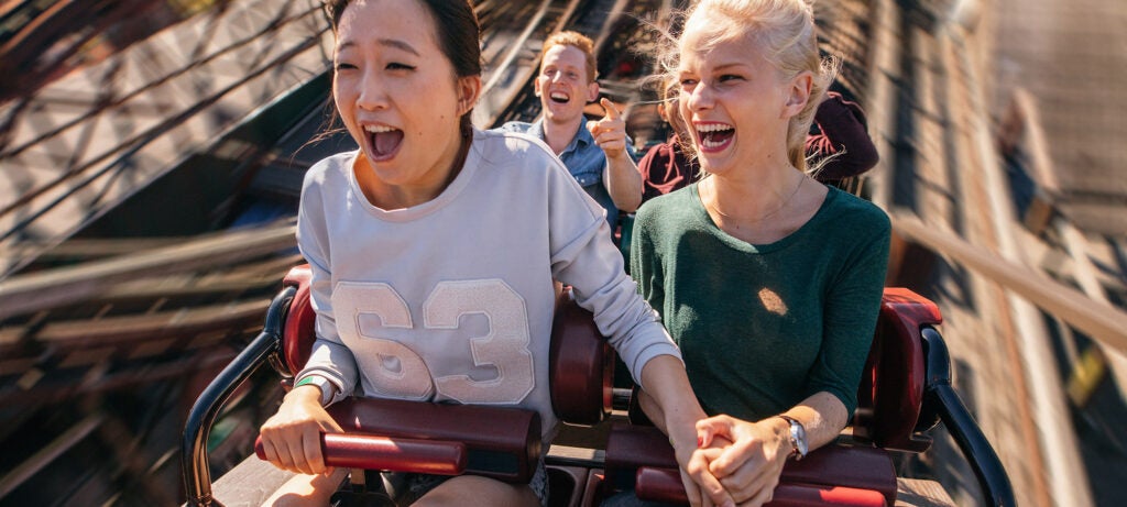 happy young people riding a roller coaster