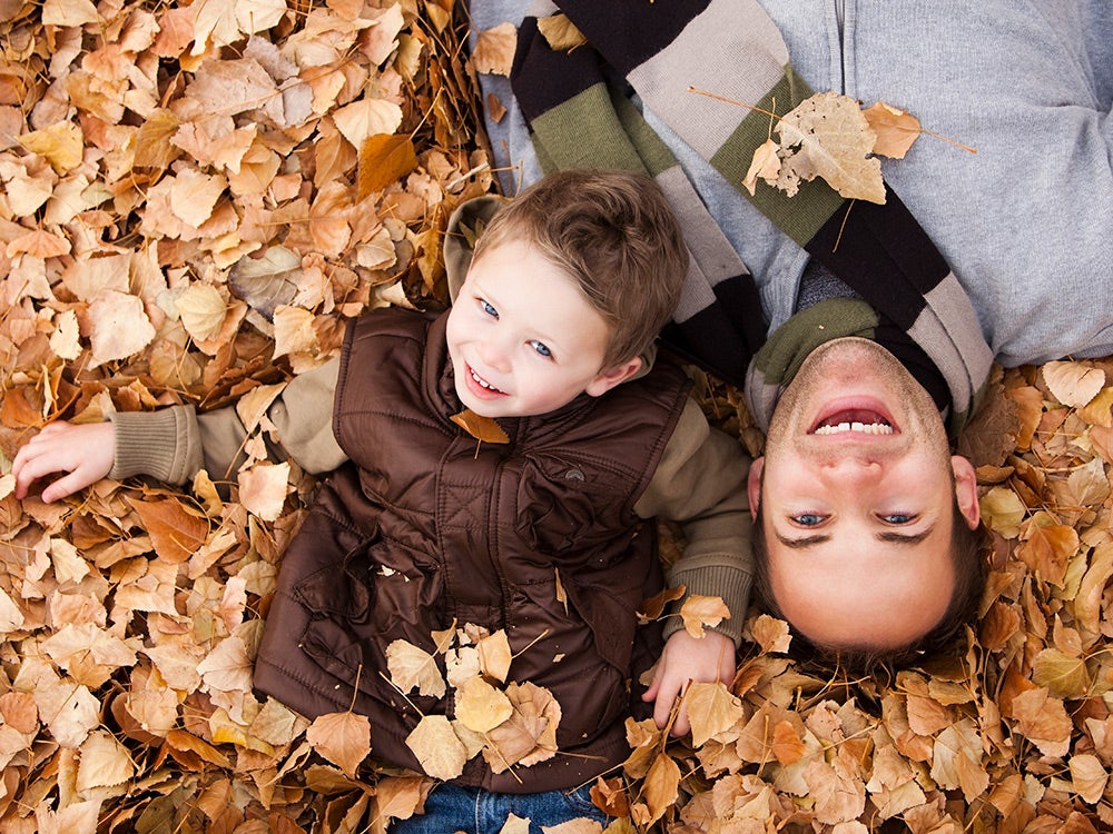 Father and son laying in autumn leaves