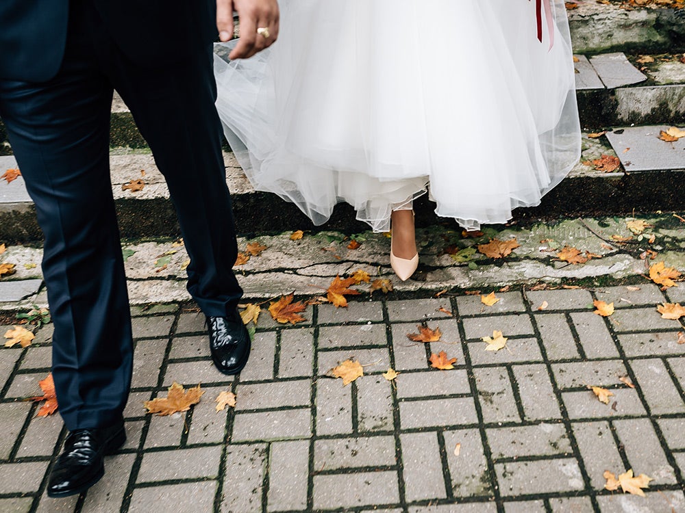 The bride and groom walk along the autumn leaves