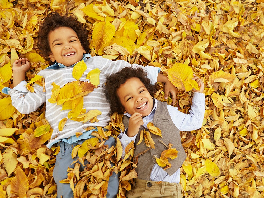 Twins laying in yellow autumn leaves