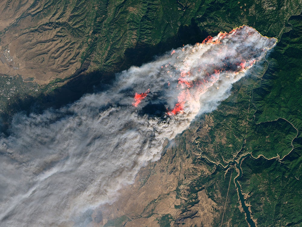 a satellite view of a massive plume of smoke and fire