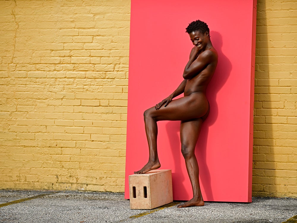 naked athlete posing in front of pink background