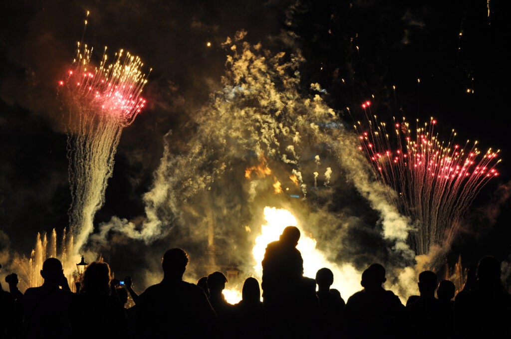 humans silhouetted against fireworks display