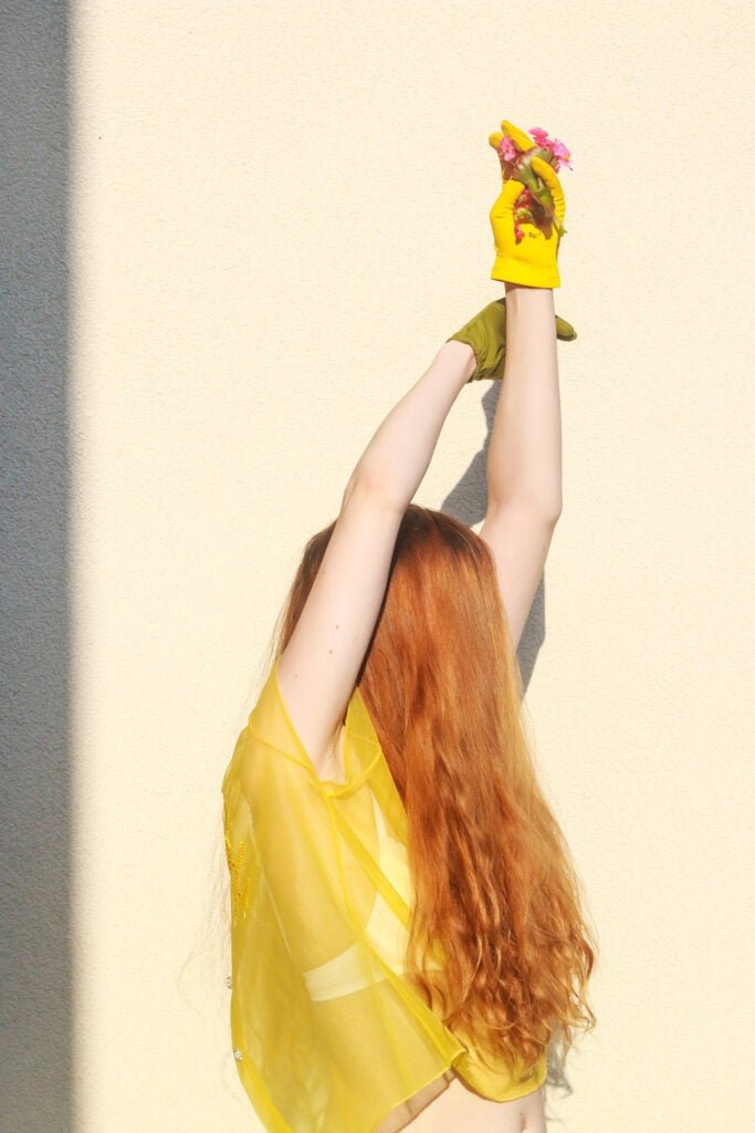 girl in yellow with red hair and yellow glove holding flowers