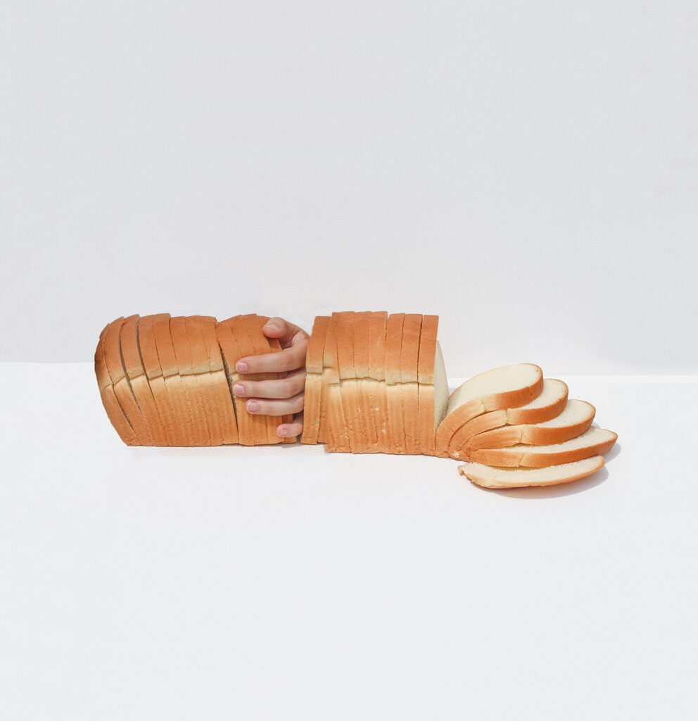 hands in loaf of bread on white background