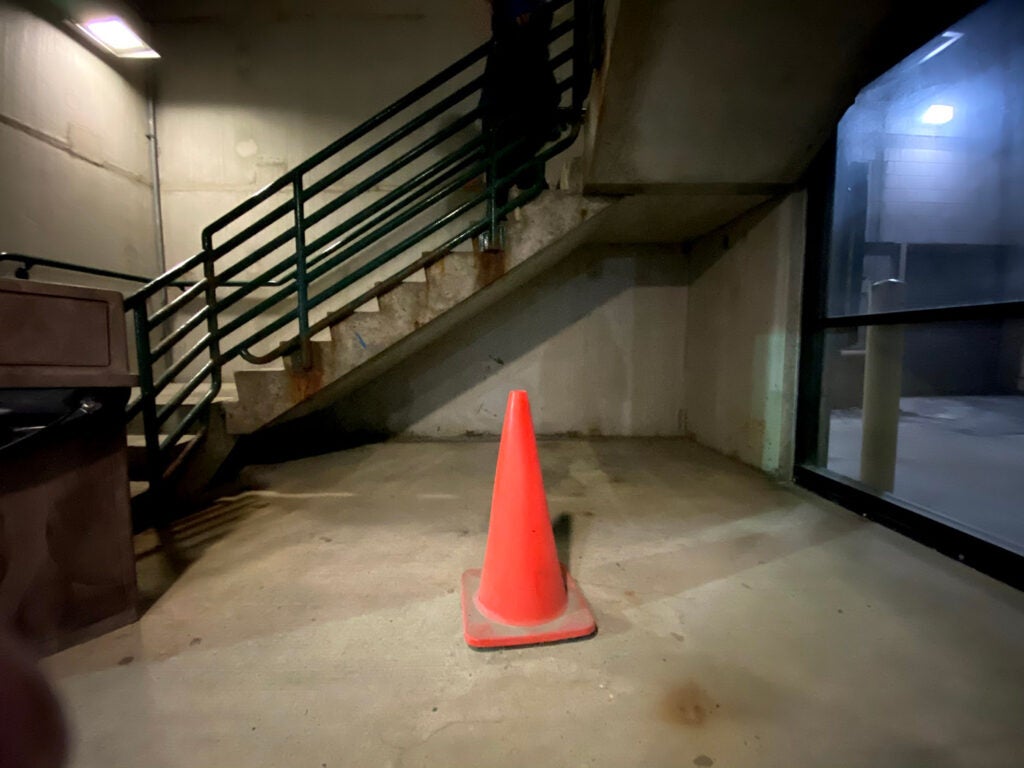 An orange cone under a staircase