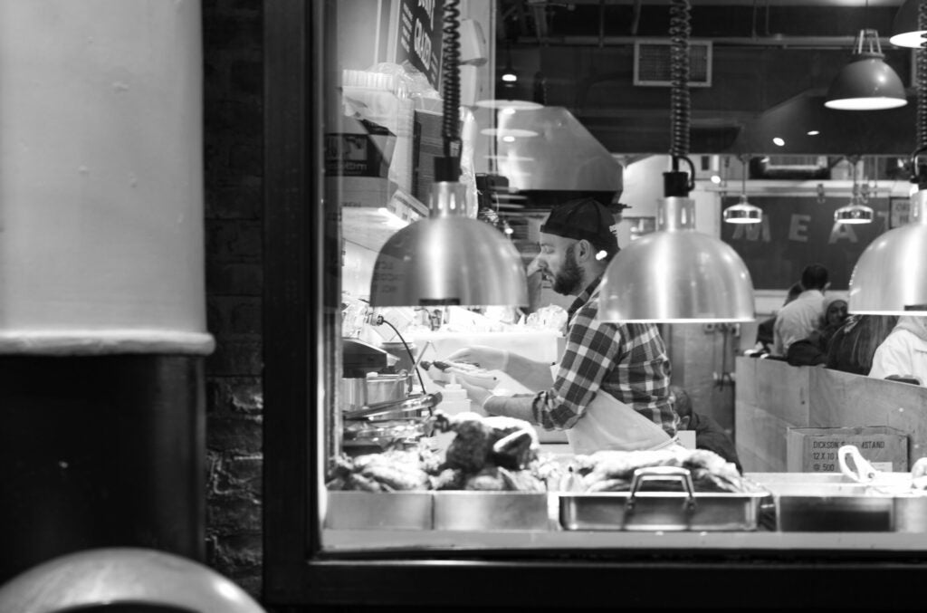 A man prepares fancy hot dogs in Chelsea Market
