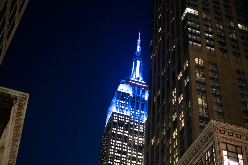 Empire state building lit up blue at night