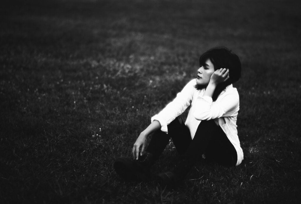 black and white image of woman sitting in grass