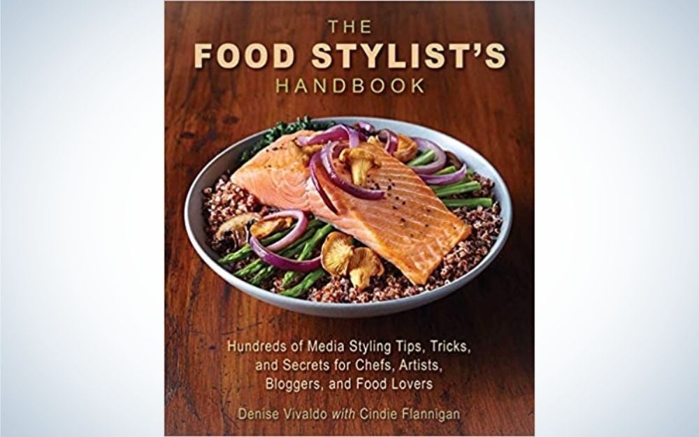 The cover of The Food Stylist's Handbook with brown background and with a cooked salmon plate in the middle of it.