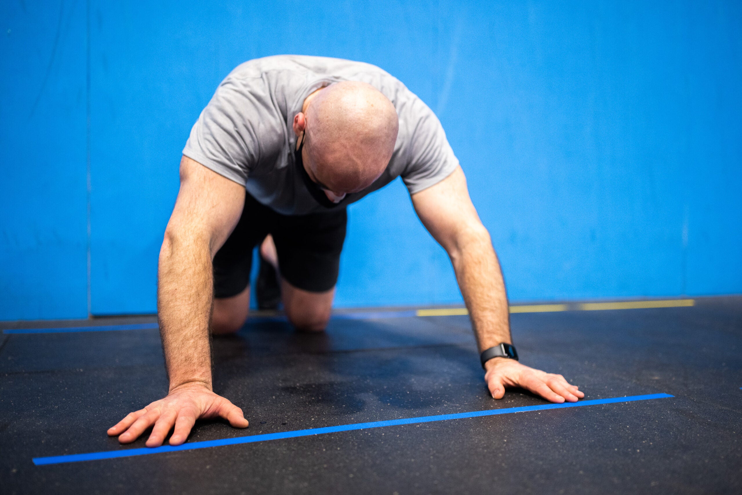 A man on hands and knees on an exercise mat, doing push ups