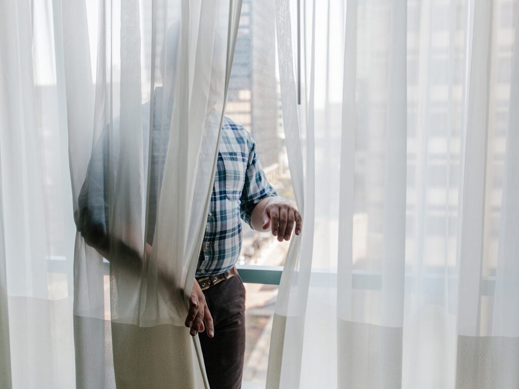 man hidden behind sheer curtain