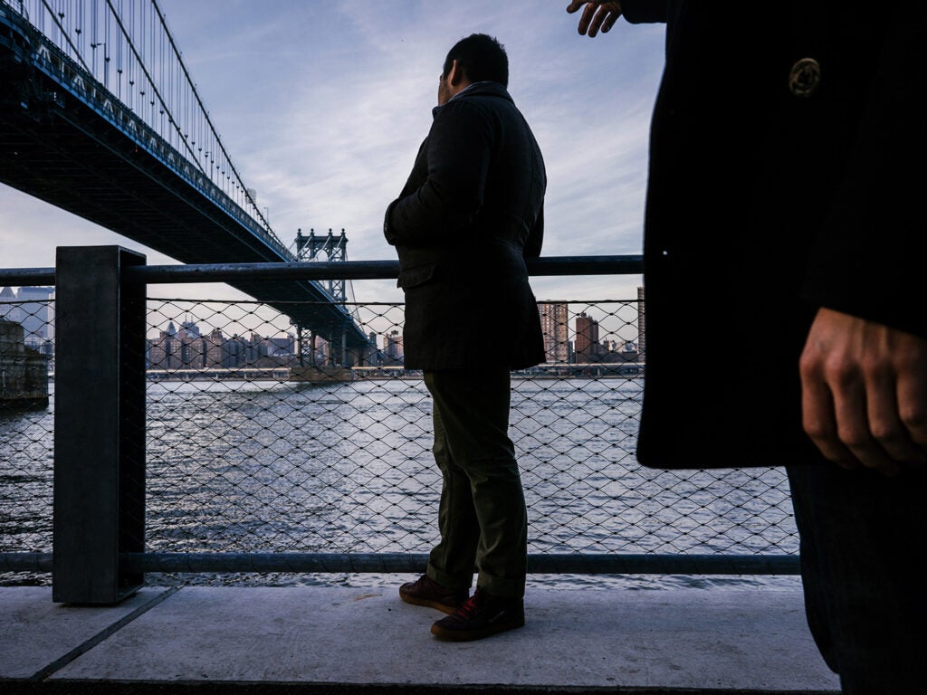 two men looking over fence at river