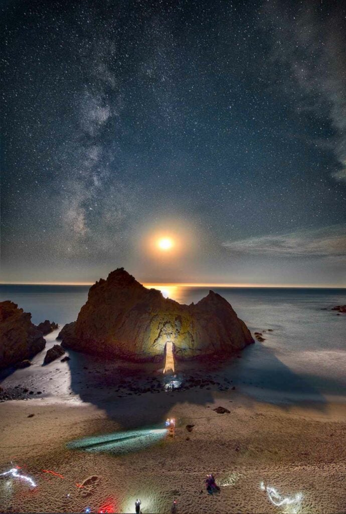 We All Know How The Sun Sets Through The Keyhole At Pfeiffer Beach In The Winter Months, But You Can Also Capture The Light From The Setting Moon Too. Night Photography Has Exploded Along The California Coast Recently Because There Are So Many Amazing Coastal Landmarks To Use As A Foreground Subject In Front Of The Milky Way. Last Year A Famous Photographer Known For His Artistic Milky Way Images Posted A Photo Of The Milky Way Over Pfeiffer Rock With The Light Of The Moon Beaming Through The Keyhole. Here, One Year Later, Is A Photo Of Photographers From All Over The World Trying To Copy His Shot.