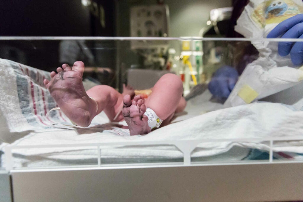 Brand new baby feet kicking away in the hospital warmer while the nurse preps for baby's first diaper.