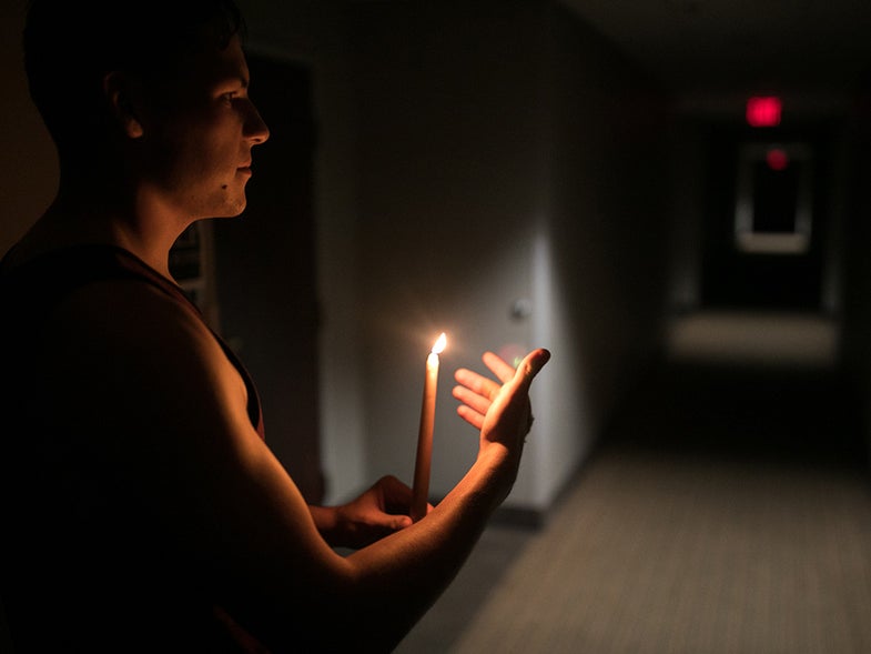 man holding a candle in dark room