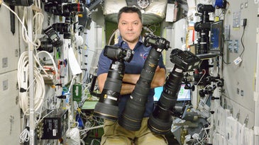 Russian Astronaut Poses With Floating Nikon Cameras on the International Space Station