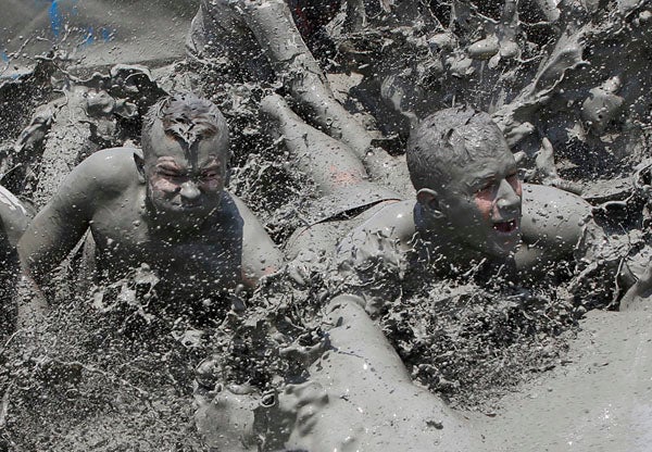 Foreign visitors play with mud during the 14th Boryeong Mud Festival at Daecheon beach in Boryeong, about 190 km (118 miles) southwest of Seoul, July 17, 2011. Around 2 to 3 million domestic and international tourists visit the beach during the festival each year to enjoy mud activities such as mud slides, mud wrestling and mud massages. The festival runs from July 16-24 this year.  REUTERS/Jo Yong-Hak (SOUTH KOREA - Tags: SOCIETY IMAGES OF THE DAY TRAVEL)