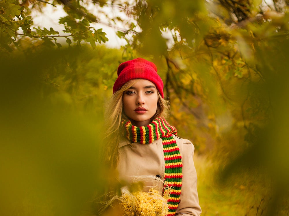 A woman wearing a knit hat and scarf in autumn