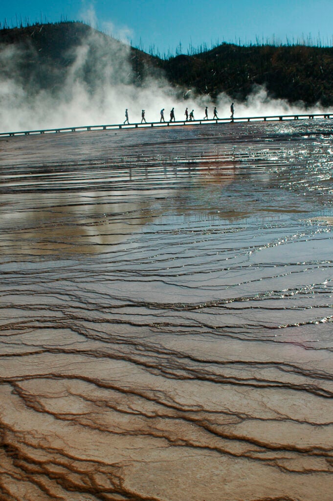 Photo: Madelyn Carr Bonnett This photo was shot in the hot springs area of Yellowstone National Park near Old Faithful Geyser and Inn. I was shooting in the opposite direction from the same boardwalk my subjects are on when I turned around to see this perfect scene with them in front of the steam and the reflection in the hot water running down the worn rock ledges. I quickly stooped to get as low as possible and got two shots off before most of the visitors had moved away from the steamy background. CAMERA: Nikon D70 FOCAL LENGTH: 28mm SHUTTER SPEED: 1/160 sec. LENS: Sigma Telephoto/Macro APERTURE (F-STOP): f/9