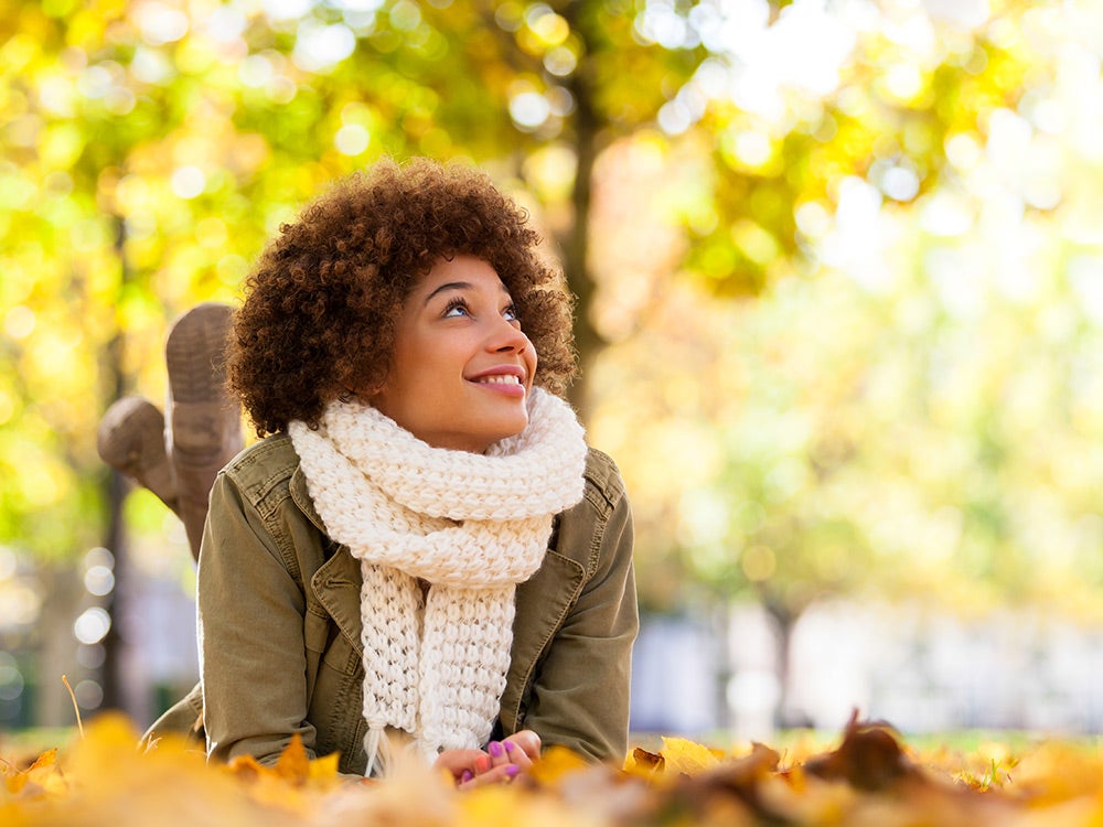 Young smiling woman lying on fall leaves