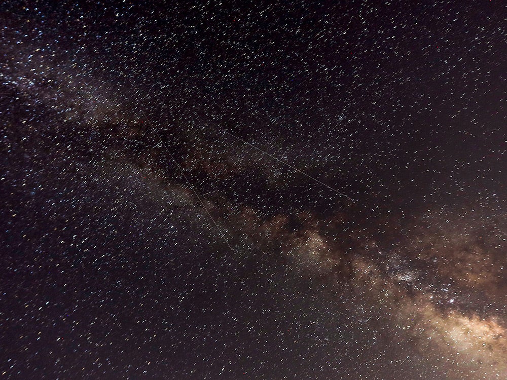 Meteors crossing the night sky past the Milky Way