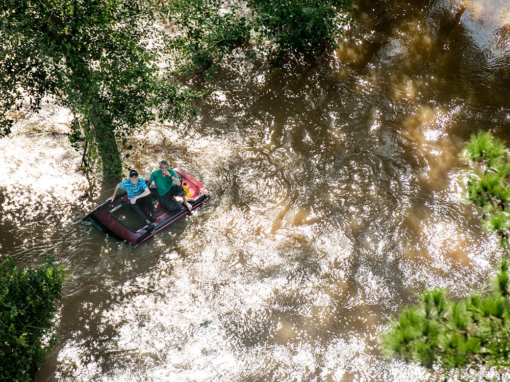 two people on roof of flooded vehicle