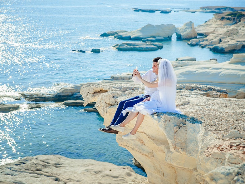 married couple taking selfie on a cliff