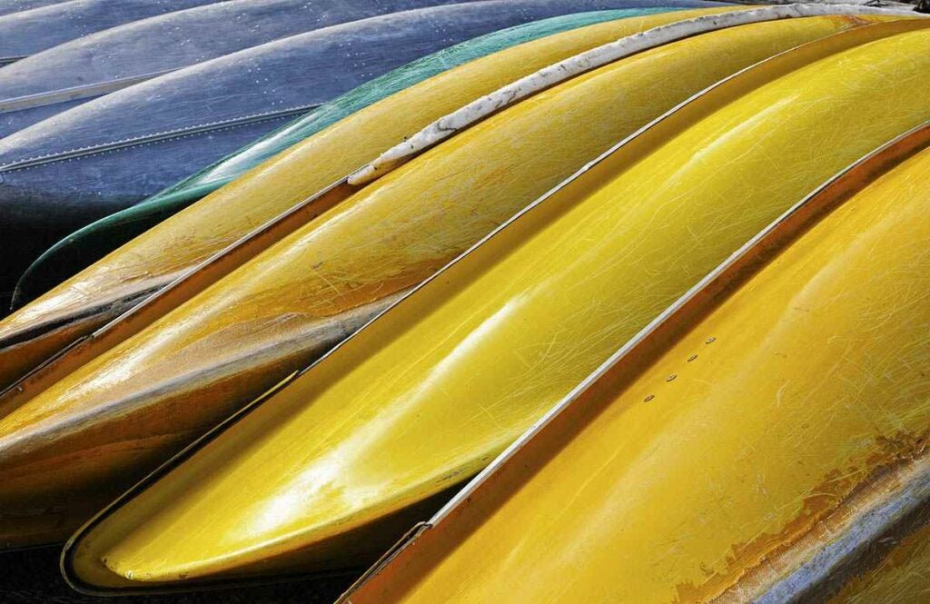 Canoes stacked along a lake.