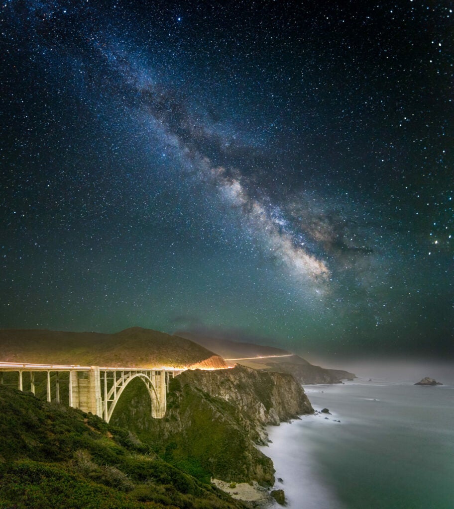 Photo: Christopher Axe I returned to Bixby Bridge after photographing it before in an attempt to include the Milky Way in the image. This time a did a three image panorama. The foreground and bridge was exposed for 5 minutes at f2.8 and ISO 1250 the additional sky images were exposed at f2.8 for 30 seconds at ISO 2000. The light streak is of a south bound car. CAMERA: Canon 5D Mark III FOCAL LENGTH: 14mm SHUTTER SPEED: 5 minutes LENS: Canon 14mm f2.8 L ISO: 1250 APERTURE (F-STOP): f2.8