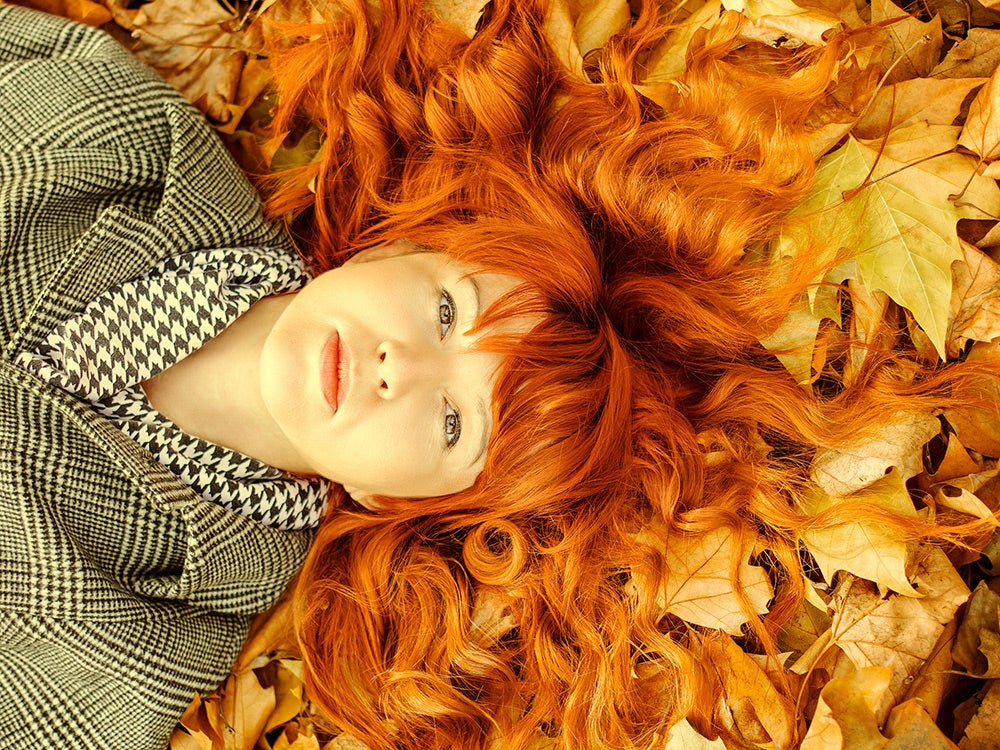 Close-Up Portrait Of Young Woman Lying On Dry Fallen Leaves