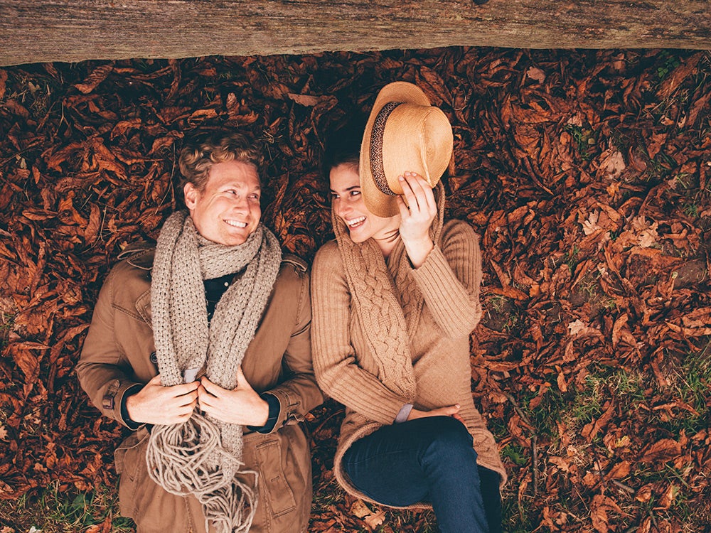 Young couple lying side by side on autumn leaves in a park