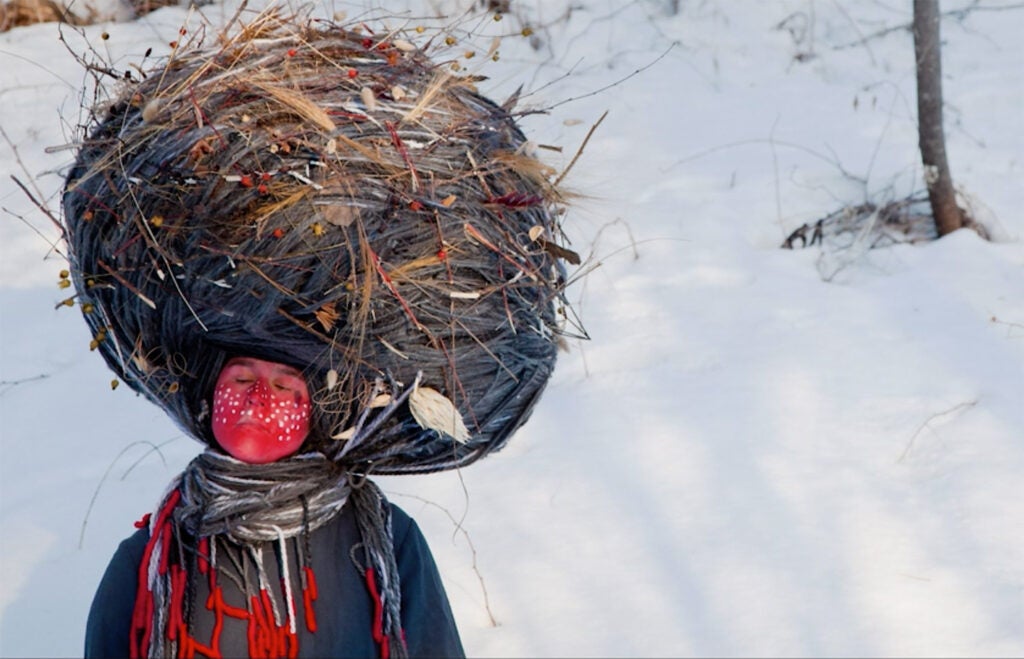 woman painted red with giant nest on her head