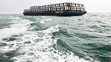 barge on the ocean carrying subway train cars