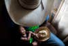 a baby in a man's lap holding a tiny cowboy hat