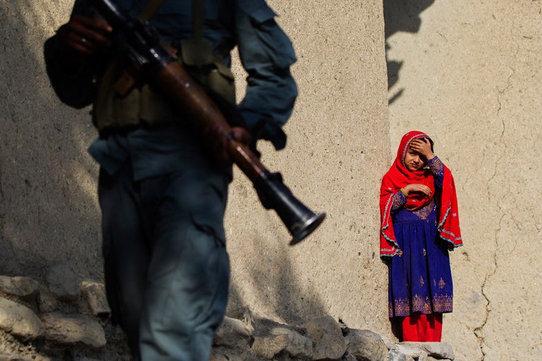An Afghan girl watches as a member of the Afghan Uniformed Police walks past with paratroopers from Chosen Company of the 3rd Battalion (Airborne), 509th Infantry on a helicopter assault mission to improve their biological database, near the town of Ahmad Khel in Afghanistan's Paktiya Province July 16, 2012. Picture taken July 16. REUTERS/Lucas Jackson (AFGHANISTAN - Tags: CIVIL UNREST MILITARY TPX IMAGES OF THE DAY)
