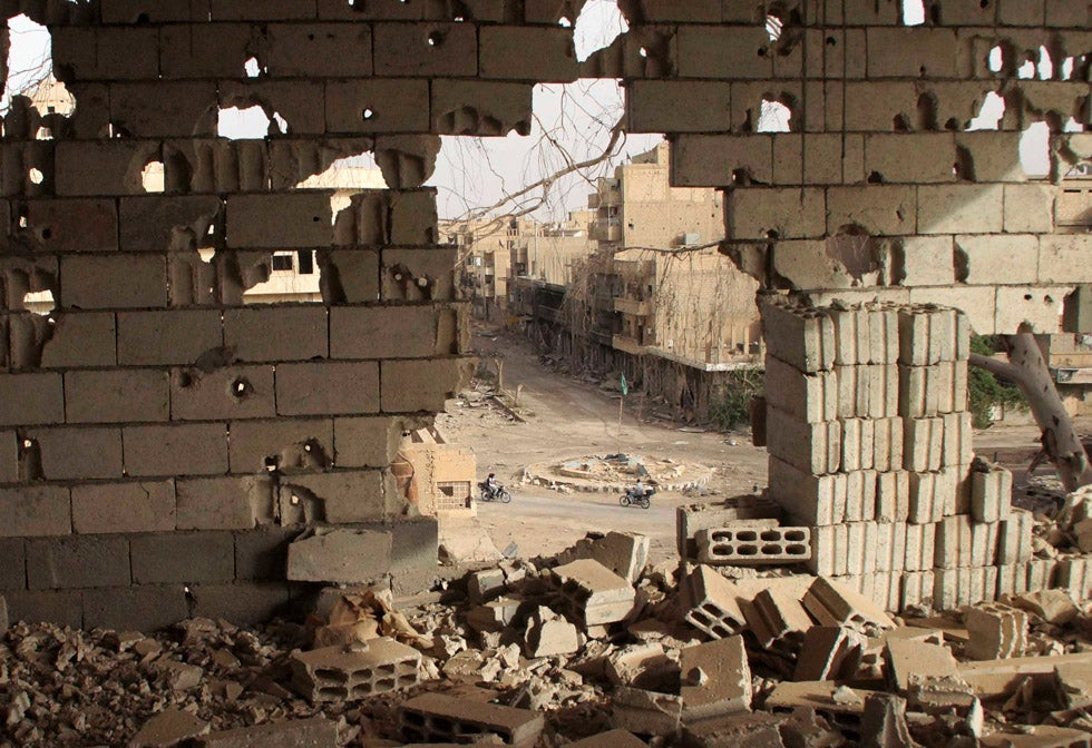 People riding on motorcycles are seen through a hole in a damaged building in Deir al-Zo, Syria. Khalil Ashawi is a freelance photographer, covering the war in Syria as a stringer for Reuters.