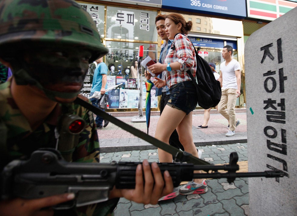 Pedestrians walk past a soldier participating in an anti-terror drill at a subway station in Seoul, South Korea. Kim Hong-Ji is a photojournalist working for Reuters out of South Korea. See more of his work on his <a href="http://kimhongji.net/">personal site</a>.