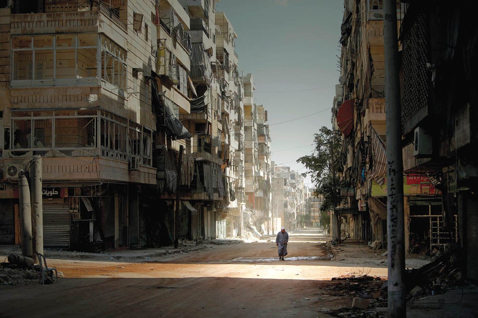 A Syrian man holds his robe while walking in the partially destroyed Salaheddin neighbourhood of Aleppo, under the control of teh Syrian army on September 3, 2012.  Syrian troops backed by artillery and warplanes fought rebels on multiple fronts on September 5 as peace envoy Lakhdar Brahimi described the death toll as "staggering" and destruction "catastrophic."  AFP PHOTO/JOSEPH EID        (Photo credit should read JOSEPH EID/AFP/GettyImages) APH0213_Images of the Year