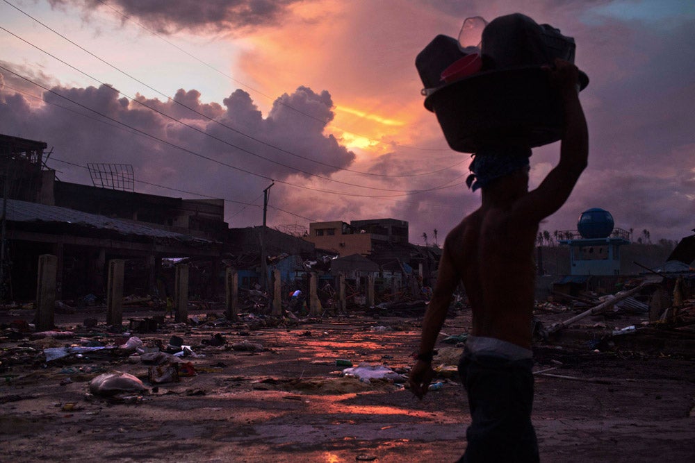A Typhoon Haiyan survivor carries his belongings through the ruins of Tacloban, Philippines on his way back to his temporary shelter.