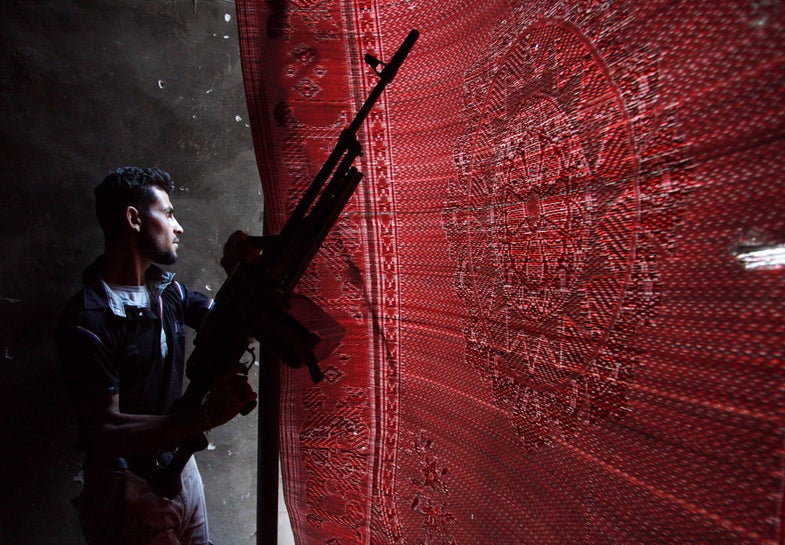 A Free Syrian Army fighter carries his weapon as he peeks through a mat erected as protection from forces loyal to Syria's president Bashar al-Assad in Deir al-Zor July 25, 2013. Picture taken July 25, 2013. REUTERS/Khalil Ashawi (SYRIA - Tags: CONFLICT POLITICS CIVIL UNREST) - RTX11ZIF