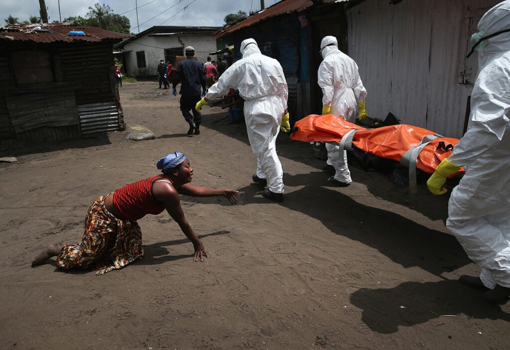 Current Affairs Photographer of the Year | Caption: A woman crawls towards the body of her sister as Ebola burial team members take her away.
