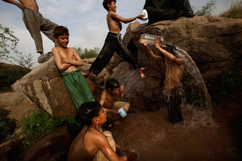 Pakistani boys, who make a living by collecting recyclable materials and selling them to a recycling factory, shower in a pool of water created by a broken water pipe following their daily work, on a roadside on the outskirts of Islamabad, Pakistan, Tuesday, April 17, 2012. (AP Photo/Muhammed Muheisen)