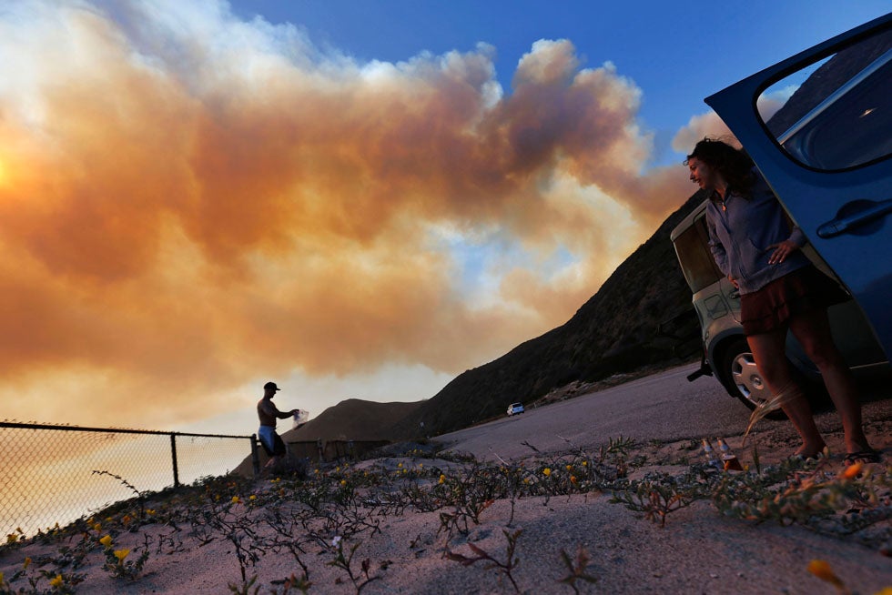 Ernie Legassey (L) and Casey Daigle return to their car after their camping trip was cut short due to a wildfire burning towards Point Mugu in Ventura County, California. Patrick Fallon is a freelance photojournalist working in and around Los Angeles, California. He shoots for a variety of publications including <em>The Los Angeles Times, Reuters, the Associated Press and the Wall Street Journal</em>.