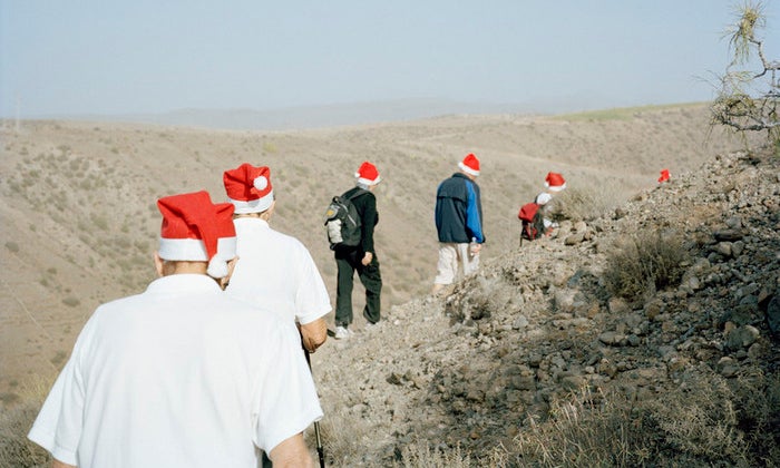 Gran Canaria, Spain. Norwegians walking in the mountains of Gran Canaria, heading for the annual Christmas service at La Plaza Noruega. La Plaza Noruega is a small, remote spot donated to the Norwegian community by the local authorities of Mogan. The red hats are mandatory on this day. Photo by Knut Egil Wang/Moment/INSTITUTE