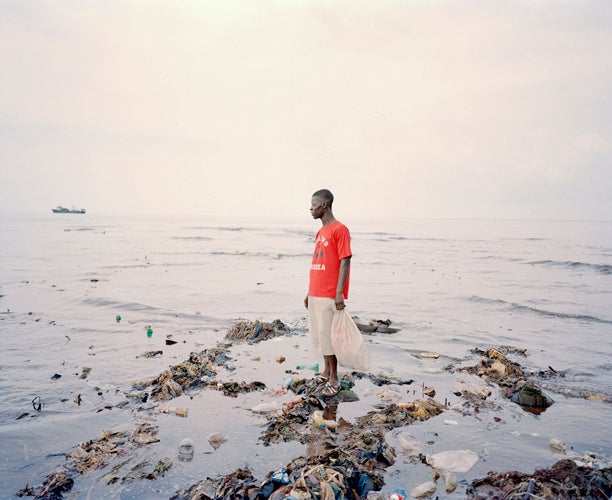 Momoh, 33, collects plastic bottles from the polluted beach of Kroo Bay, a poor slum settlement of 5,500 people in Freetown, Sierra Leone. The cholera outbreak of 2012 struck hardest in the slums, where crowded and unsanitary living conditions and unsafe water sources allowed the disease to spread rapidly through the densely populated areas. Momoh supports his family of 3 by collecting bottles from the rubbish along the waterways and filling them with chemicals from photographic studios for sale as a balm for skin irritations and skin lightening. As one of the world's poorest countries, unemployment for men in Sierra Leone is high. November 26, 2012