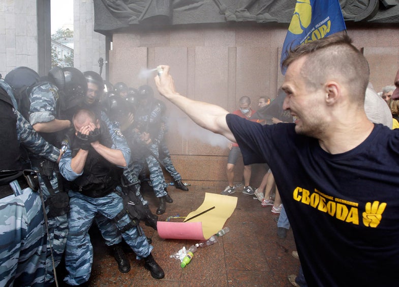 Opposition protesters spray tear gas against riot police in front of the Ukrainian House in central Kiev, Ukraine, Wednesday, July 4, 2012. Opposition activists have clashed with riot police during a protest against a controversial bill that would allow the use of Russian in official settings in Russian-speaking regions. (AP Photo/Efrem Lukatsky)