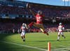 At first glance, Gonzalez's photograph of San Francisco 49ers wide receiver Michael Crabtree appears to be one of those iconic images of hard-won football glory. Look again—at the exuberance, at the opposing team standing by almost in awe. This touchdown was one of three the soon-to-be conference champions scored against the Arizona Cardinals, who ended this final regular-season game having lost 11 of their last 12 match-ups. It is Goliath beating David, with perfect theatrical lighting provided by the Almighty. When Crabtree glided through the air into the end zone, the longtime San Francisco Chronicle photographer responded with the intuition that comes with years of practice. "I reached for my short-lens [16–35mm] camera, and I don't even remember putting it up to my eye," Gonzalez says. The result: a terrific portrait. "You really get a sense of his personality," he says