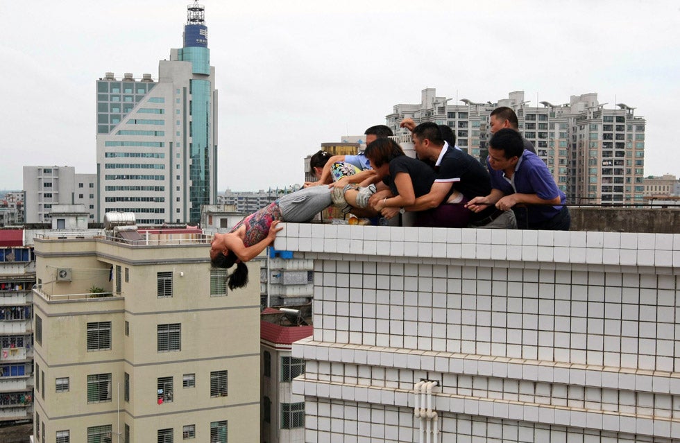 Rescuers and relatives stop a woman from committing suicide by jumping off a building in Zhanjiang, Guangdong province of China.