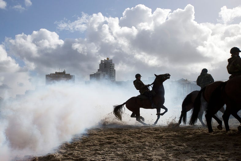 A horse bucks as it jumps over smoke from a grenade during a practice session for members of the Dutch cavalry in Scheveningen, Netherlands, Monday, Sept. 16, 2013. About 80 mounted soldiers and police were rehearsing on a beach in the coastal resort of Scheveningen, outside The Hague, for ceremonies Tuesday marking the opening of parliament. The horses were exposed to smoke grenades, and harsh sounds to reduce their chances of being startled by any incidents during the ceremony. (AP Photo/Peter Dejong)